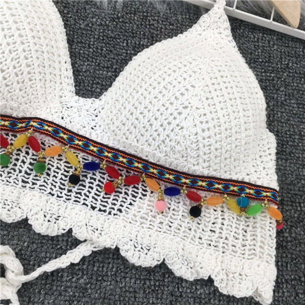 Detailed close-up of colorful woven trim with multicolored pom poms and beads on white crochet halter top.