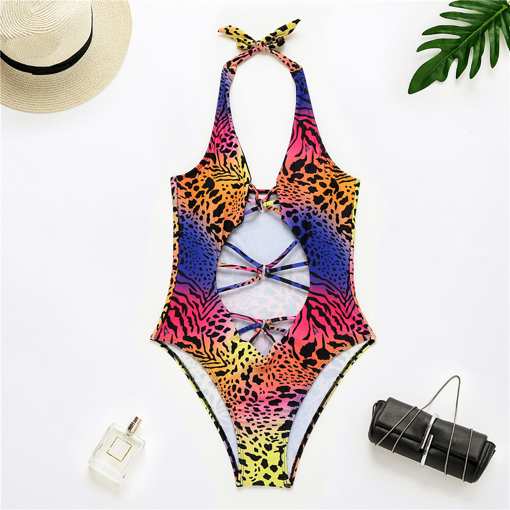 Colorful leopard print swimsuit with a hat, purse, and leaf on a white background