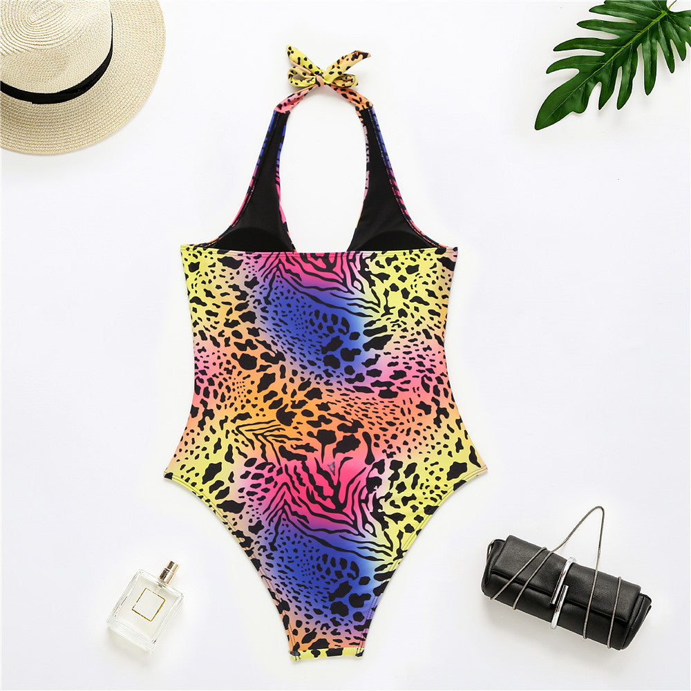 Colorful animal print swimsuit with a hat, purse, and perfume bottle on a white background