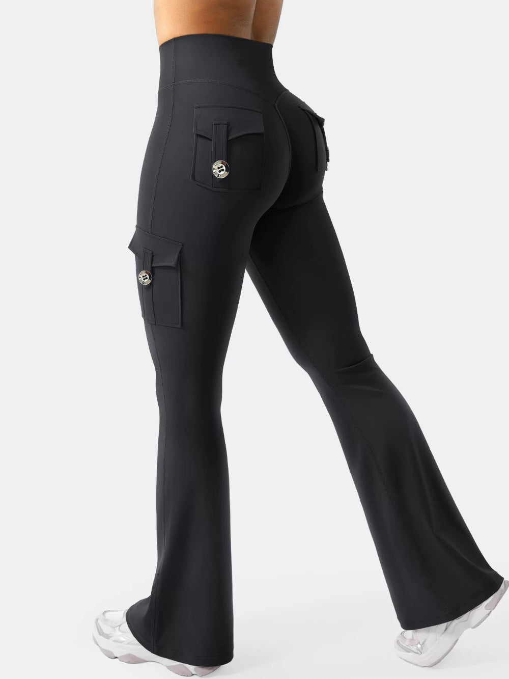 Woman modeling black high-waisted flared cargo pants with side and back pockets, shown from a rear three-quarter view against a clean white studio background.