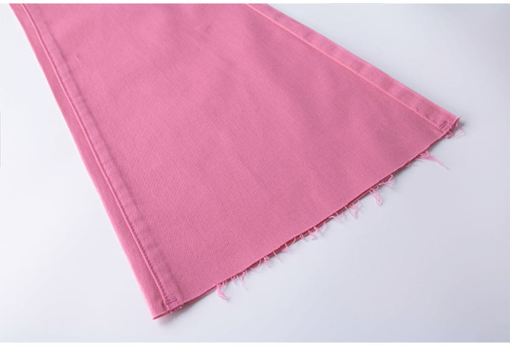 Close-up of bright pink denim-style or canvas fabric piece showing seam stitching along the edges and a raw, slightly frayed hem, displayed flat as a material sample on a plain white surface.