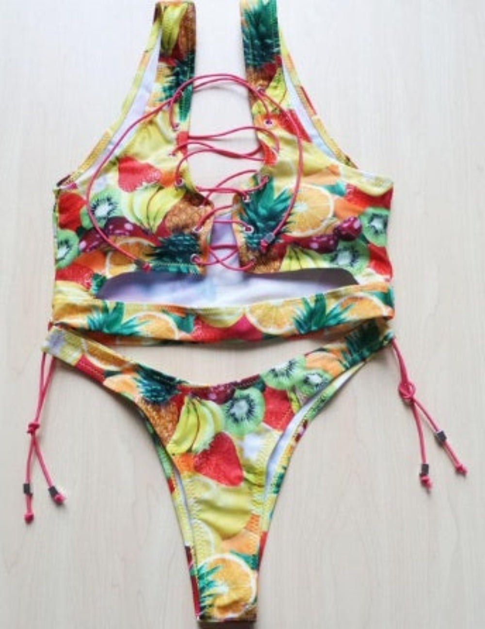 Fruit print bikini set with lace-up halter top and tie-side bottom flat lay.