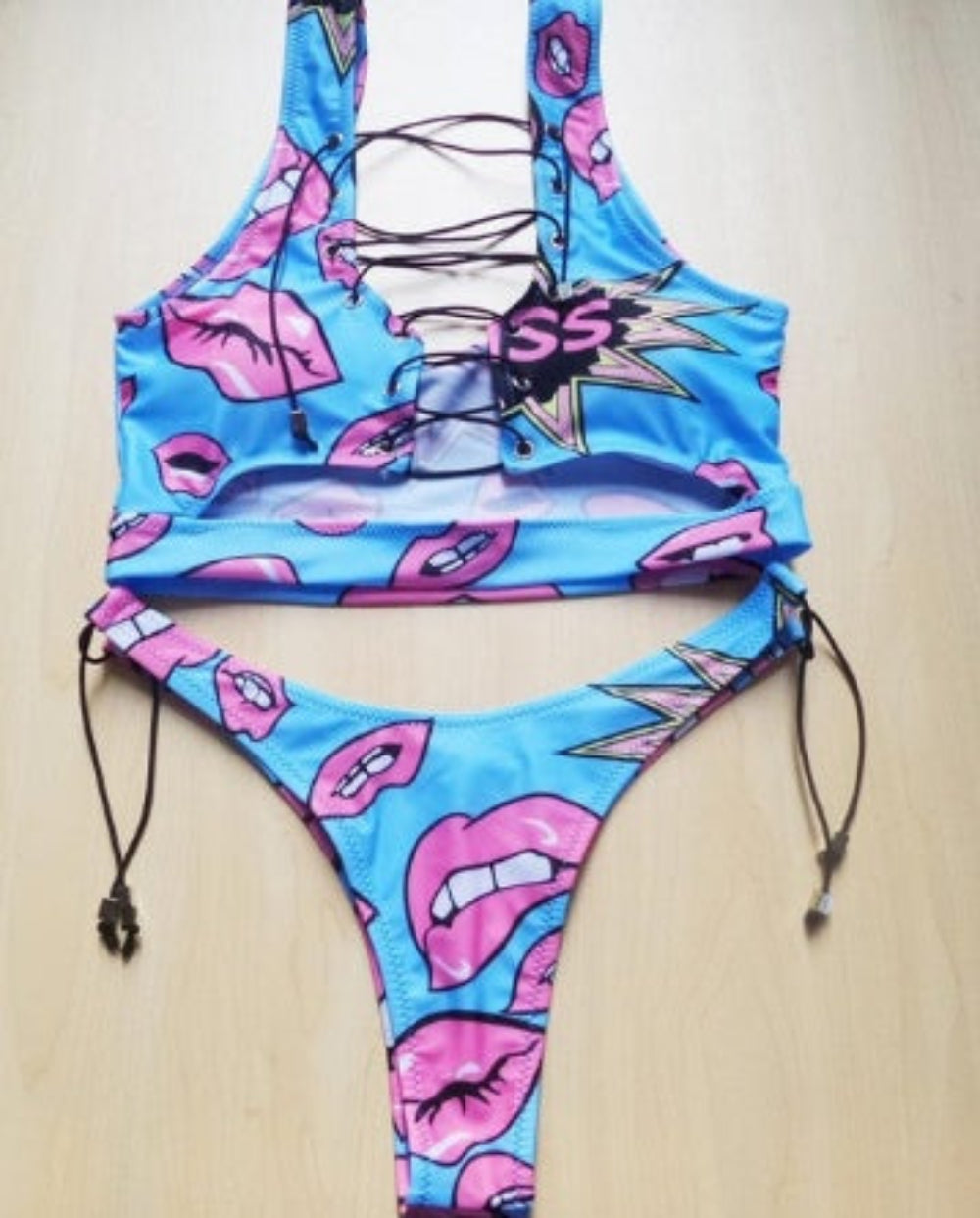Blue lip print bikini set with lace-up halter top and tie-side bottom flat lay.