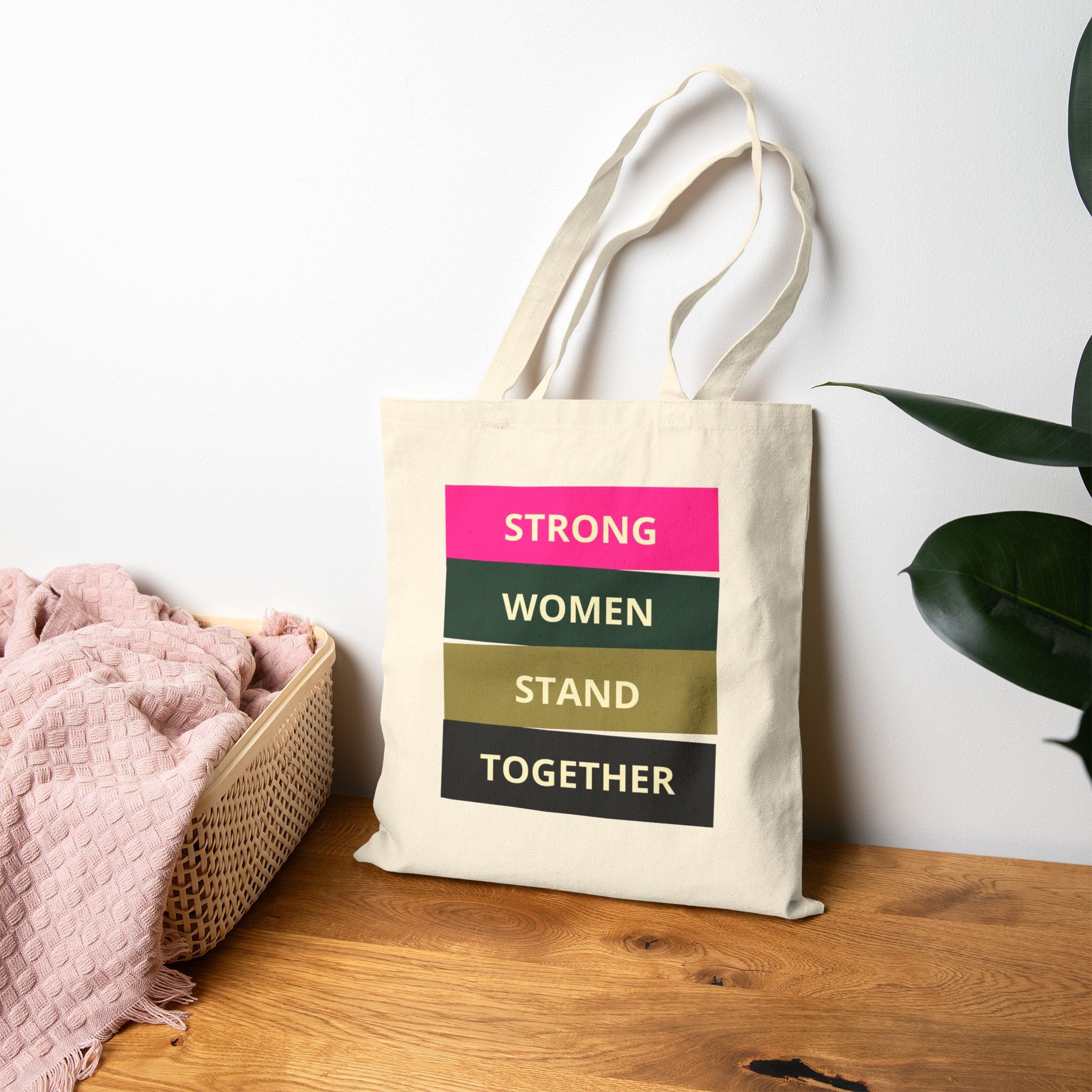 Tote bag with motivational quote on a wooden surface with a plant in the background