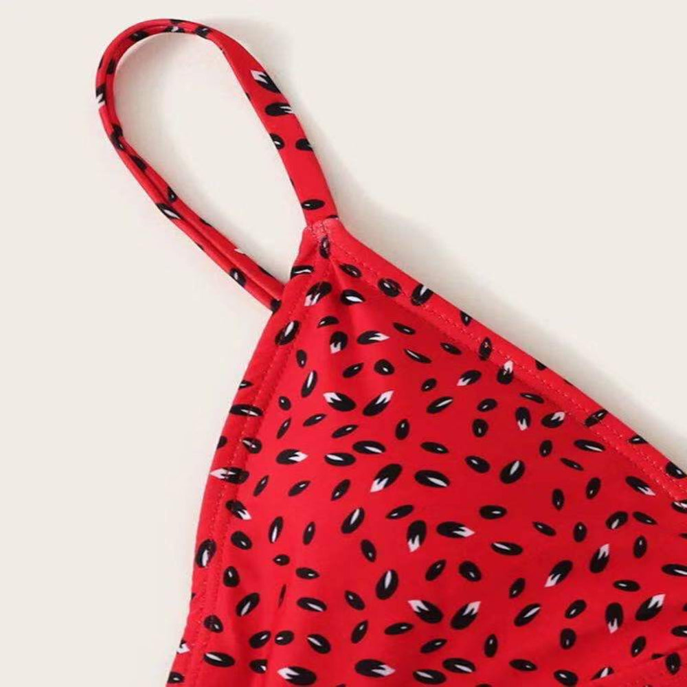 Red bikini top with black abstract pattern on a beige background
