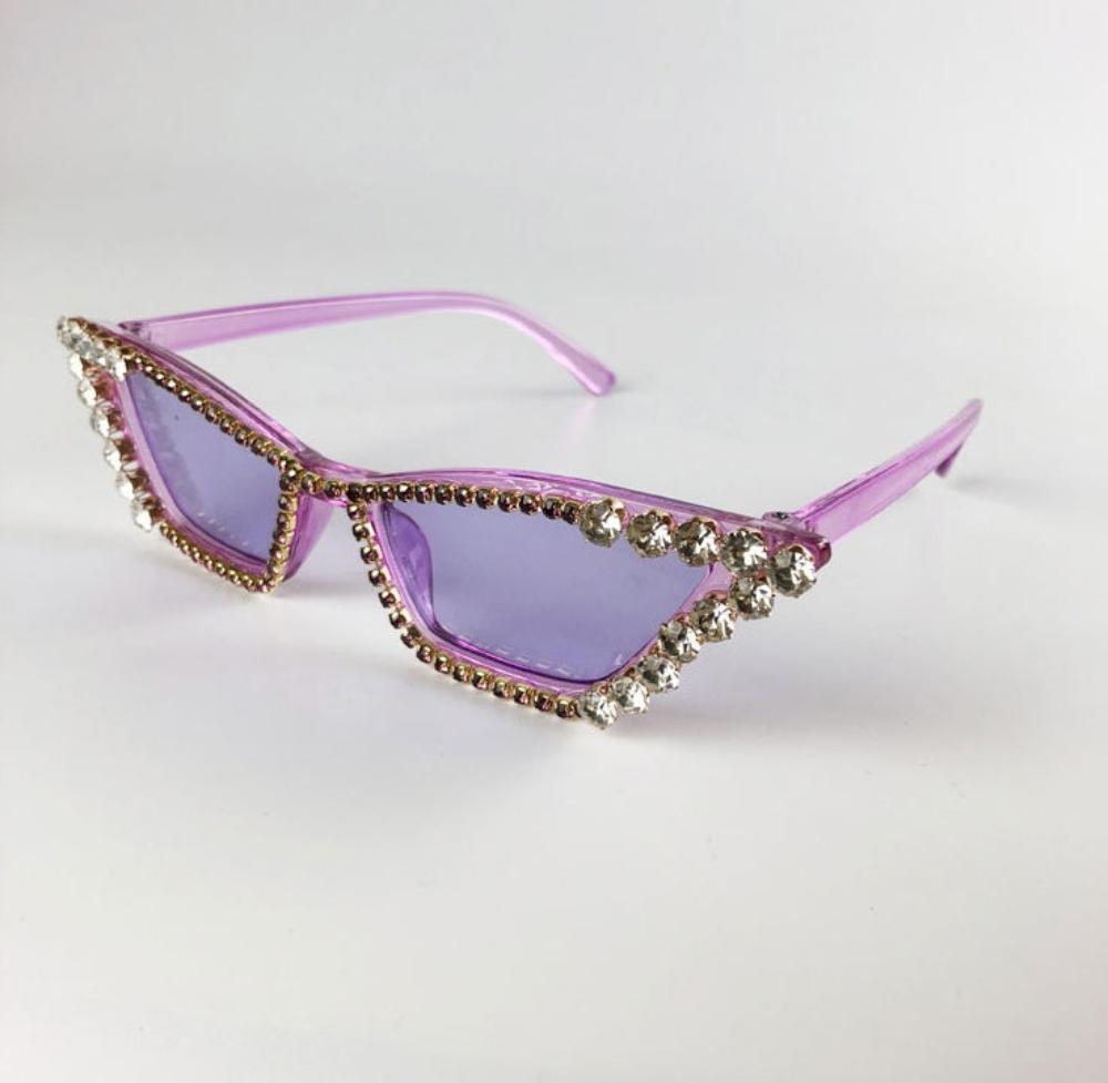 Purple rhinestone cat-eye sunglasses with purple tinted lenses and crystal trim, product photo on a white background.