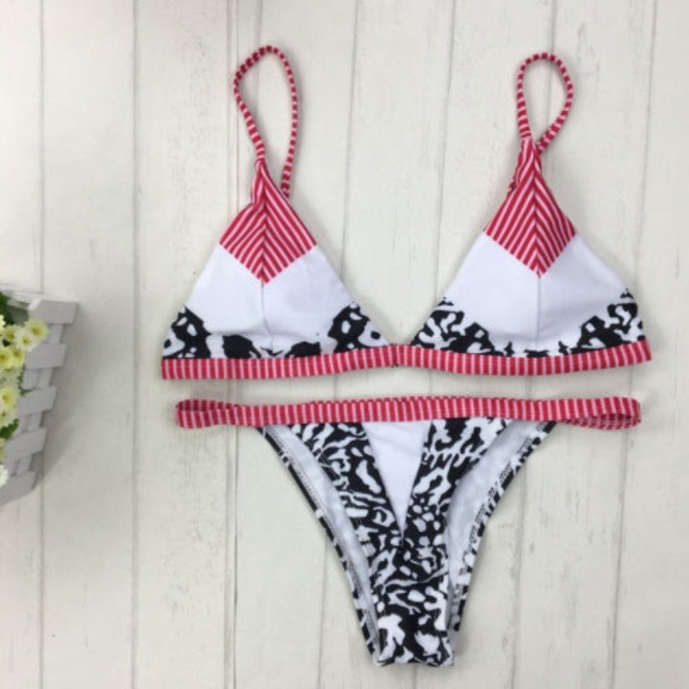 Two-piece swimsuit with red and white striped top and black and white patterned bottom on a light wooden surface.
