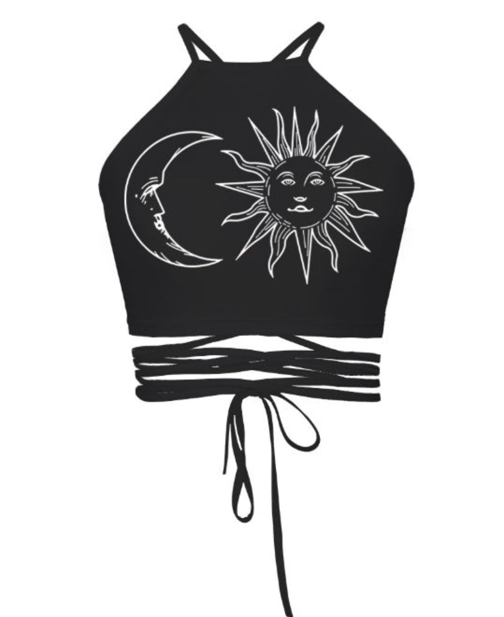 Black halter crop top with sun and crescent moon celestial graphic print and multi-strap tie-back detail, shown flat lay on white background.