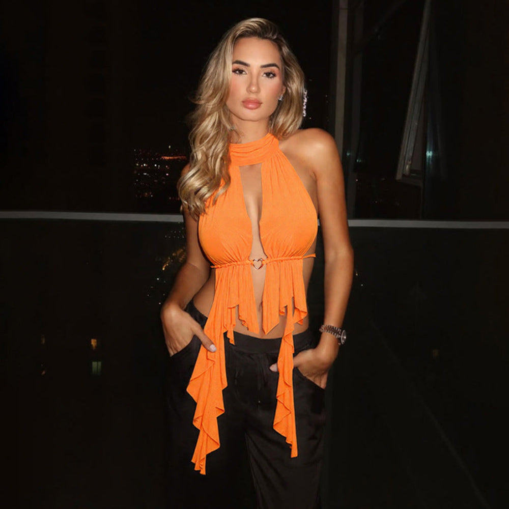 Orange halter ruffle cascade top with keyhole neckline and metal ring detail, paired with black pants, worn by a blonde model.