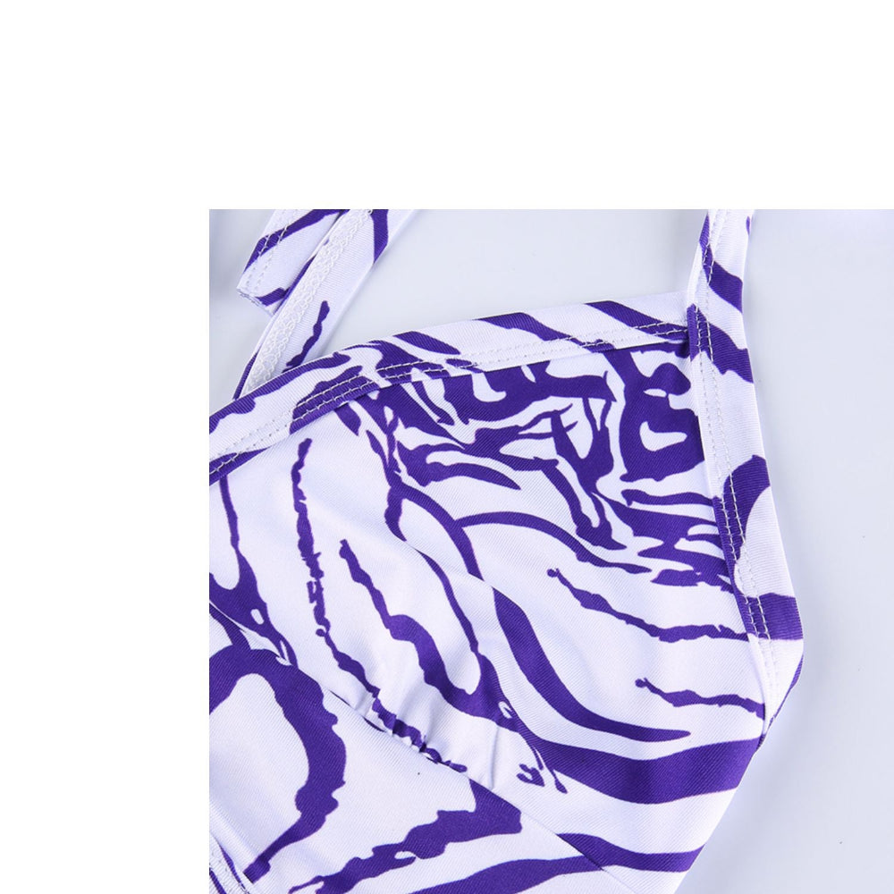 Purple and white zebra print swimsuit on a light gray background