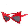 Red batwing sunglasses with rhinestone brow line and dark lenses, product photo on a white background.