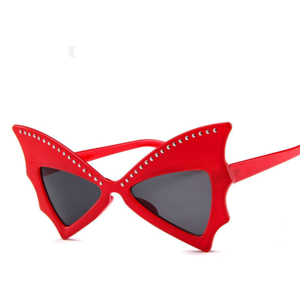Red batwing sunglasses with rhinestone brow line and dark lenses, product photo on a white background.
