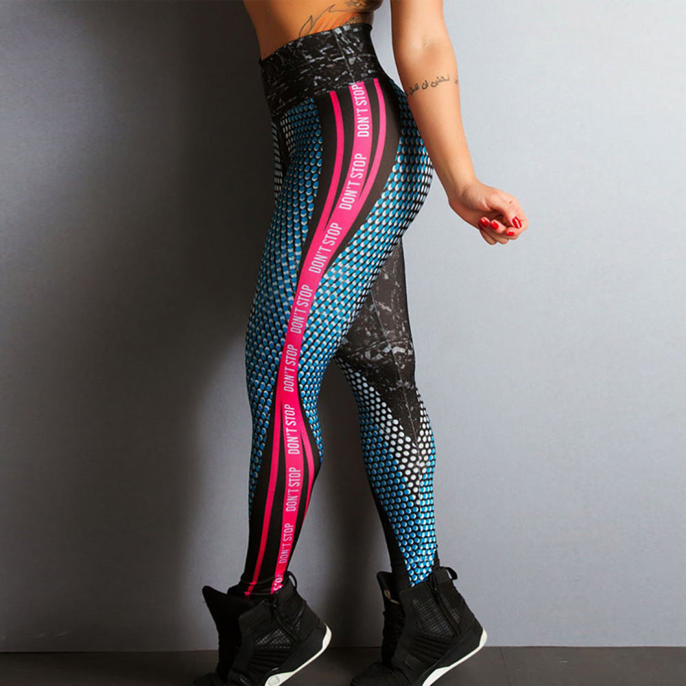 Woman modeling high-waisted athletic leggings with blue honeycomb pattern, black marble print, and bright pink side stripes featuring "DON'T STOP" text, shown from a rear three-quarter view with black sneakers against a plain gray studio background.