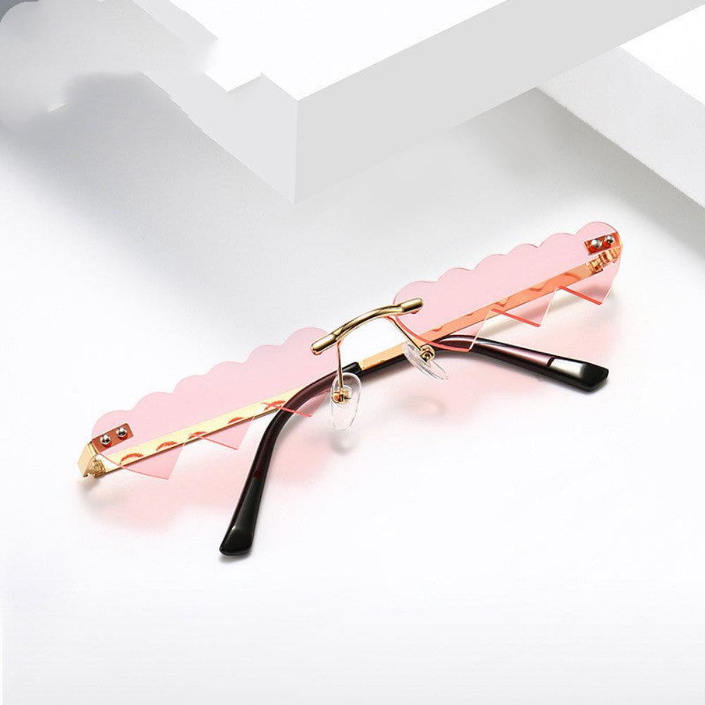 Rimless pink heart-shaped sunglasses with gold bridge and temples, product photo on a white background.