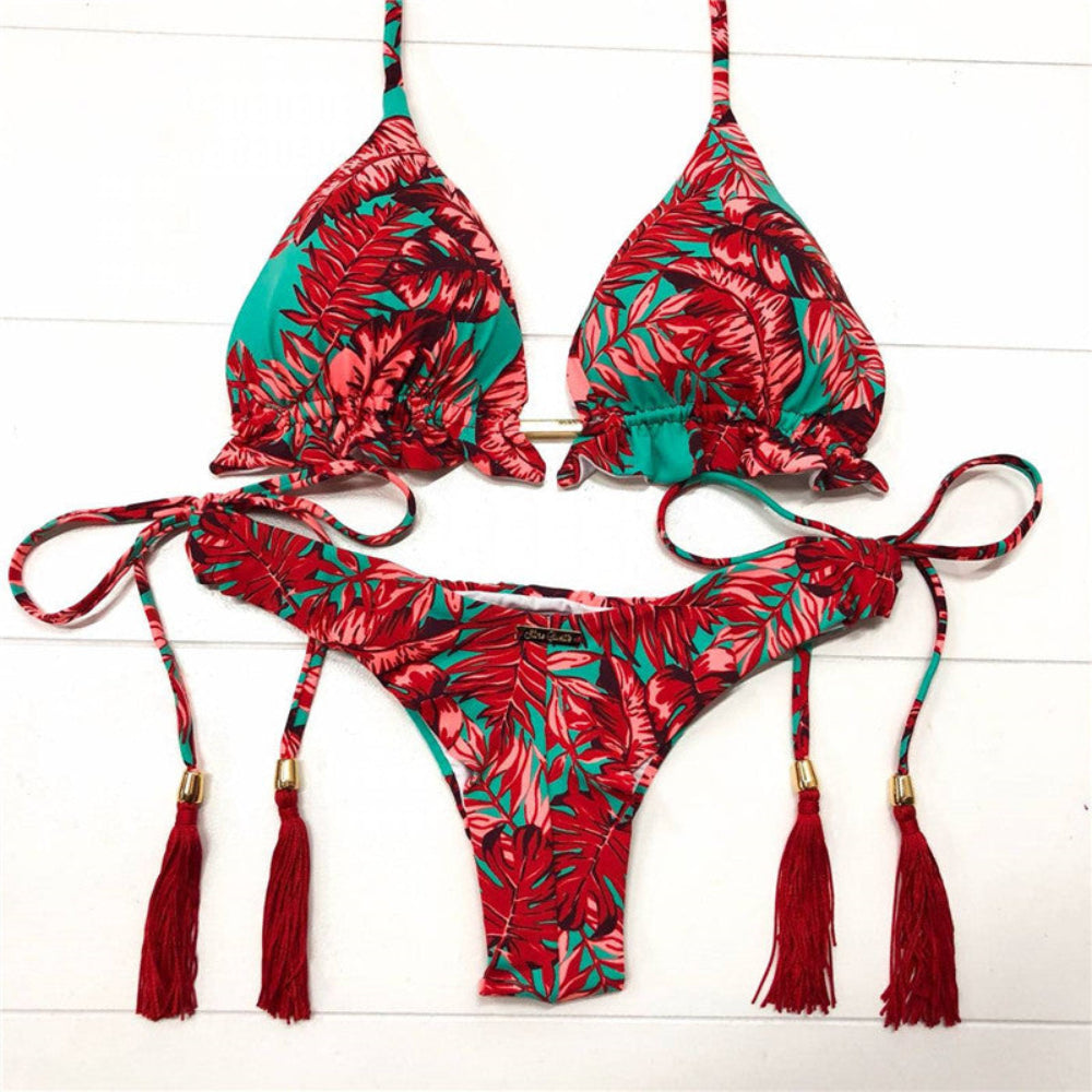 Red and green floral bikini set with tassels on a white wooden background