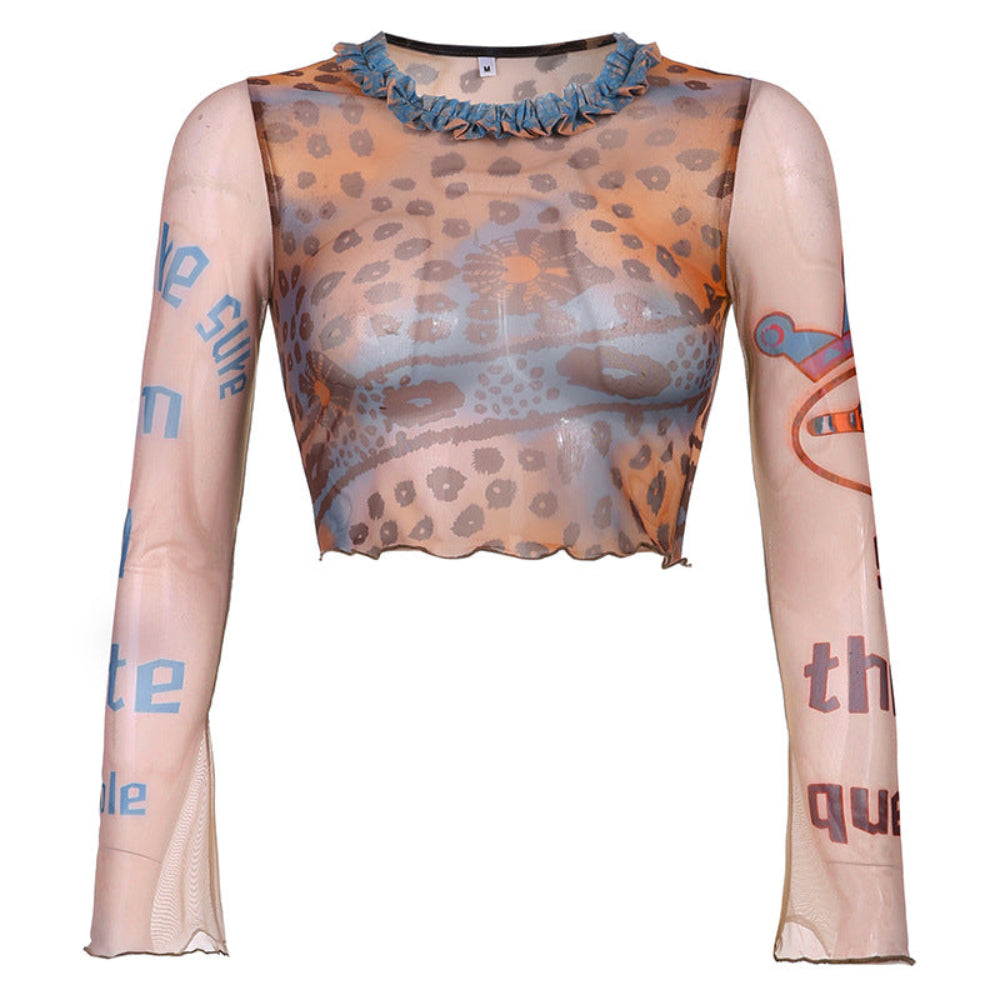 Sheer beige long-sleeve mesh crop top featuring multicolored leopard spots, paisley, and abstract patterns in brown, orange, and blue tones. It has a ruffled turquoise high neckline trim, scalloped wavy hem, and graphic text/illustrations on the sleeves with frayed distressed cuffs.