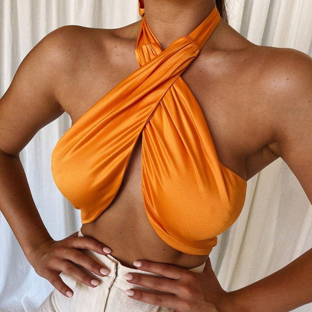Orange satin twisted halter crop top with deep plunge neckline and front knot detail, worn by a model.