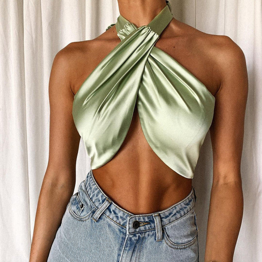 Sage green satin twisted halter crop top with plunge neckline, worn by a model with denim jeans.
