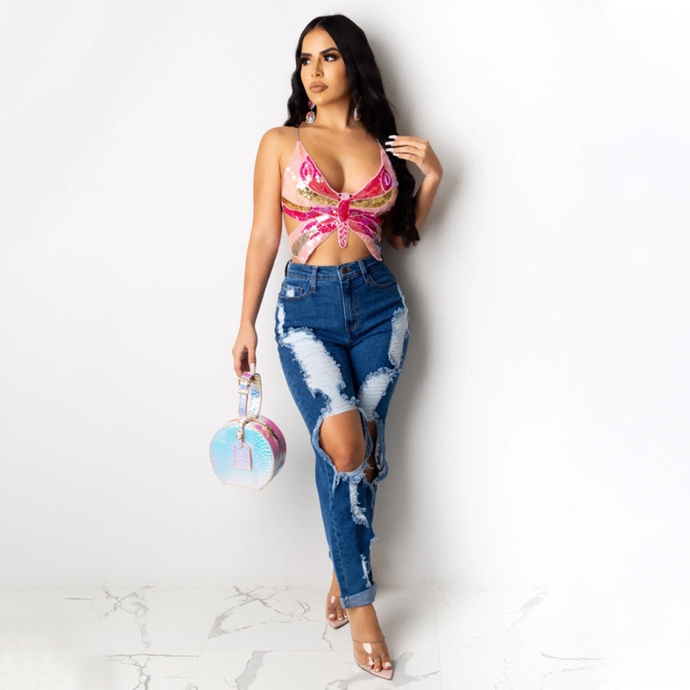 Pink sequin butterfly cut-out crop top paired with blue distressed ripped jeans, worn by a model holding a colorful round bag.