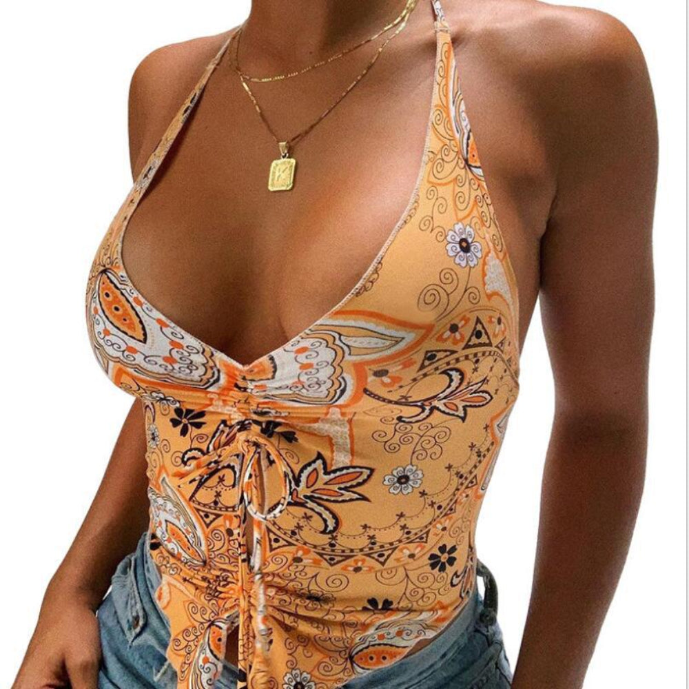 Orange paisley print halter crop top with deep plunge V-neck, front tie knot detail, and ruched sides, paired with denim jeans.