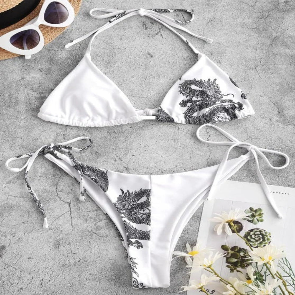 White bikini set with black floral pattern on a gray surface