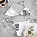 White bikini set with black floral pattern on a gray surface