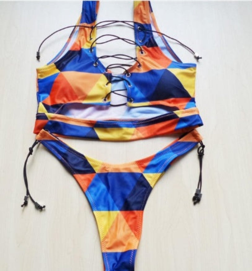 Geometric colorblock bikini set with lace-up halter top and tie-side bottom flat lay.