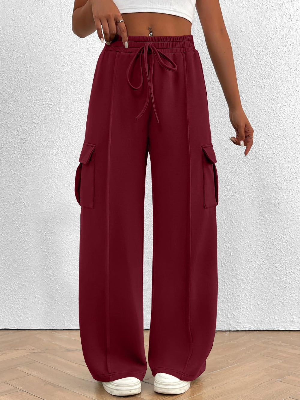 Maroon wide-leg pants with pockets worn by a person on a white background