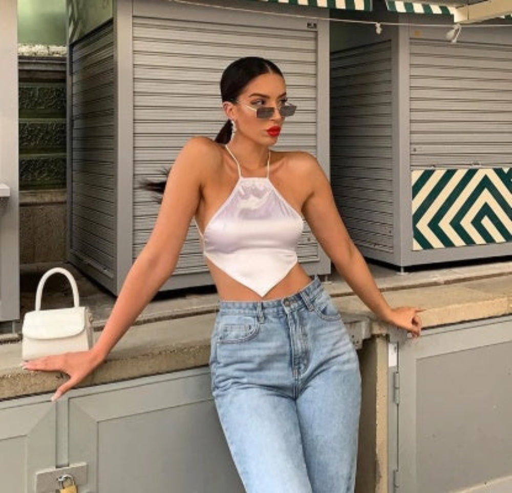 White halter cut-out crop top paired with light-wash high-waisted jeans, worn by a model.
