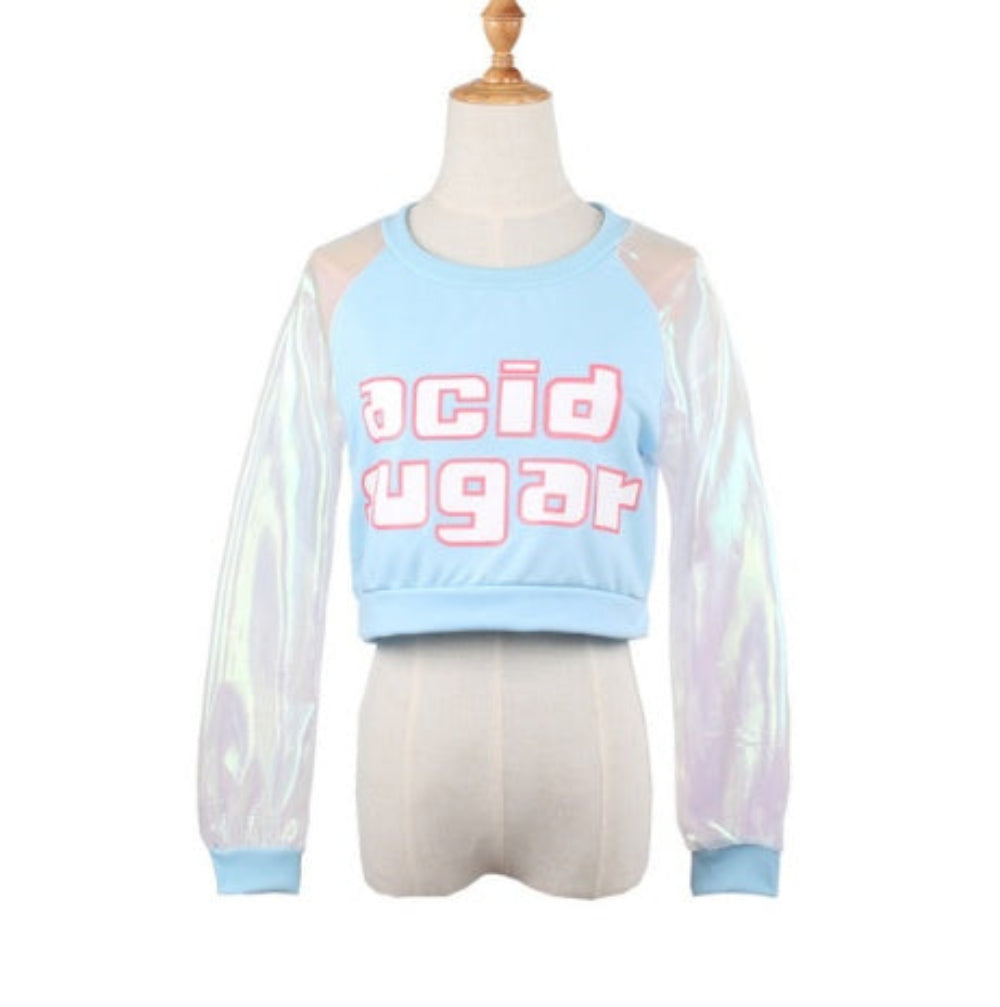 Light blue cropped sweatshirt on a mannequin featuring bold acid sugar graphic text across the chest and sheer iridescent holographic long sleeves with matching blue cuffs. The trendy Y2K-style top has a relaxed fit and round neckline.