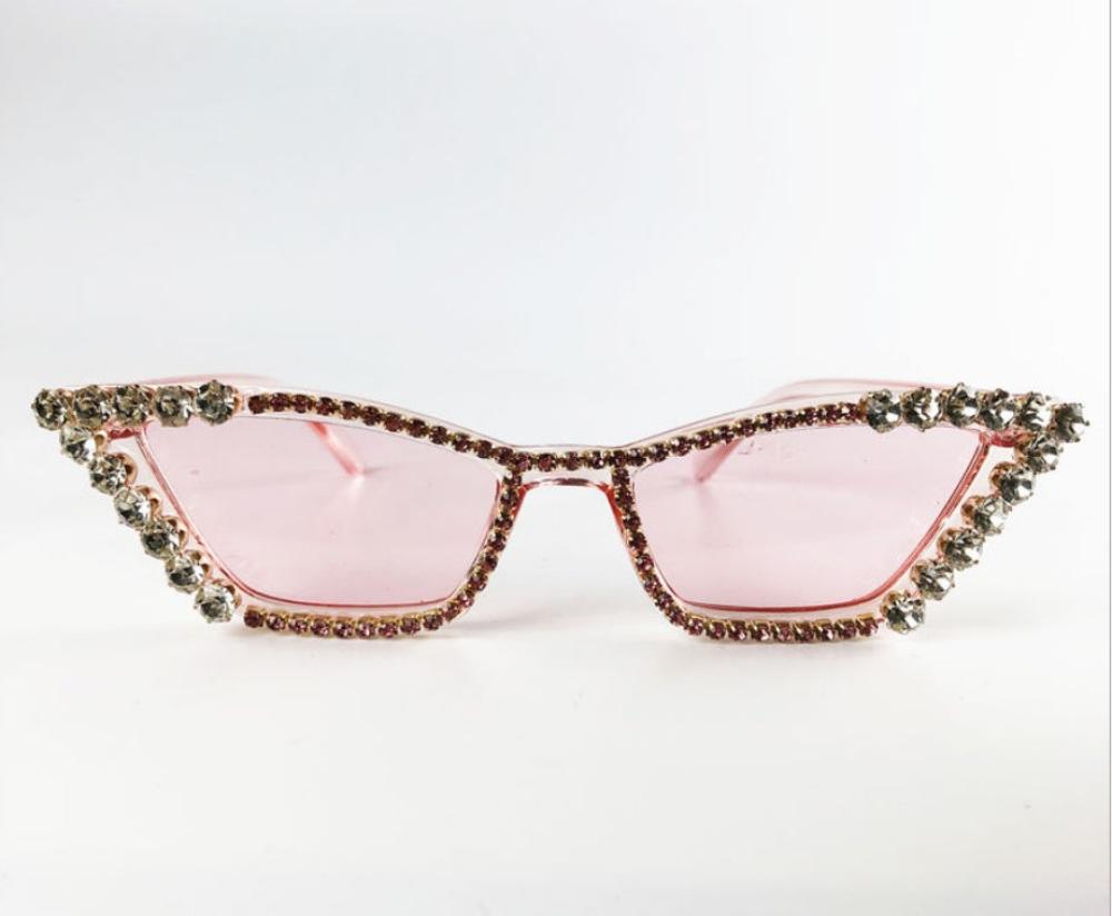 Pink cat-eye sunglasses with pink lenses and crystal rhinestone trim, product photo on a white background.