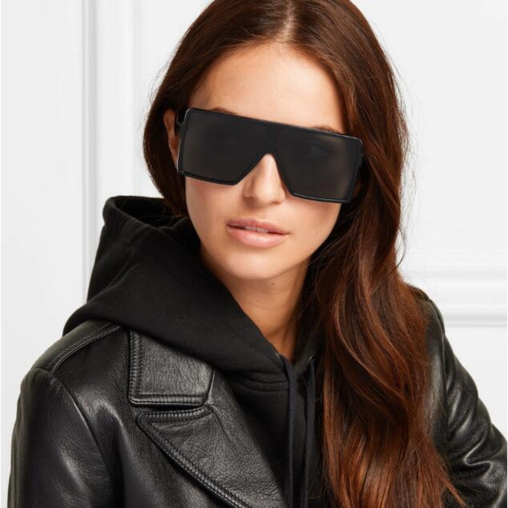 Woman wearing black sunglasses and a black leather jacket against a white background