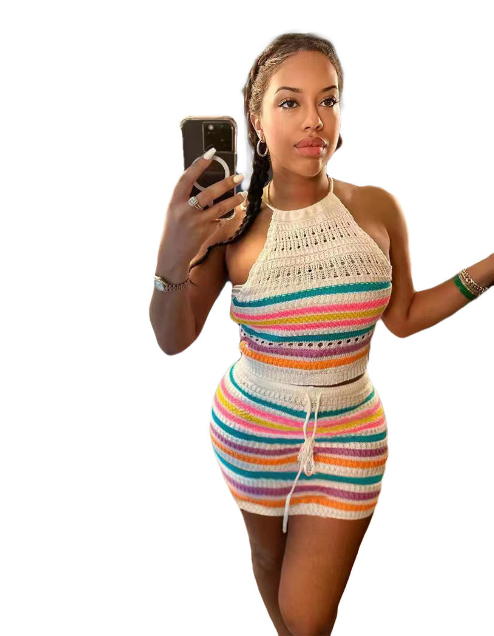 Model in a vibrant multicolored striped crochet two-piece outfit featuring a halter-neck crop top and high-waisted mini skirt with drawstring detail. Full-body pose holding a smartphone for a selfie, showcasing the textured knit fabric and bright rainbow stripes on a clean white background.