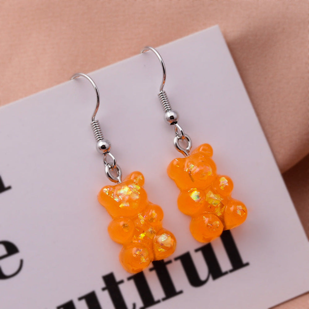 Translucent orange holographic gummy bear earrings with shimmering iridescent sparkle and silver fishhook ear wires