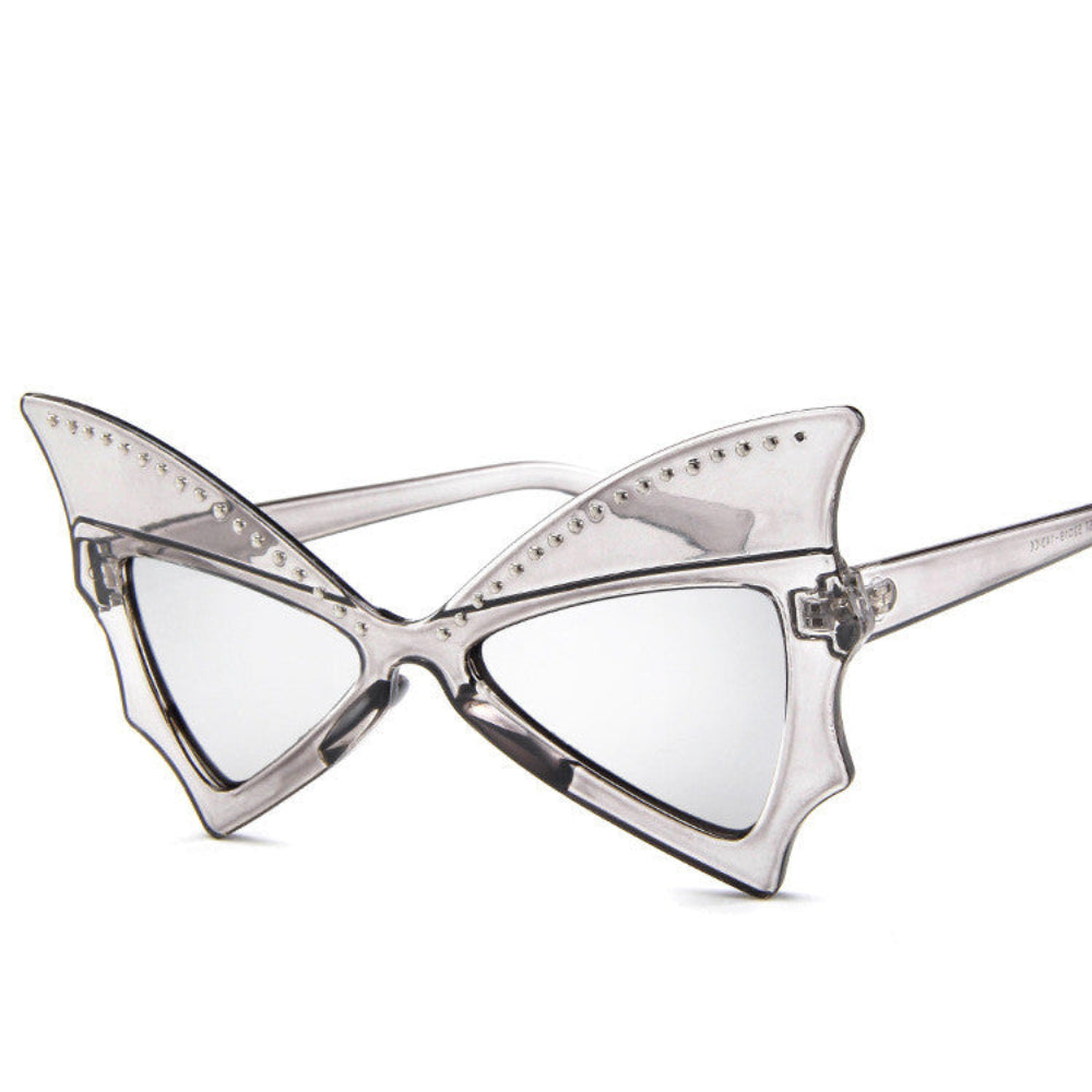 Smoke-gray translucent batwing sunglasses with rhinestone brow line and light lenses, product photo on a white background.