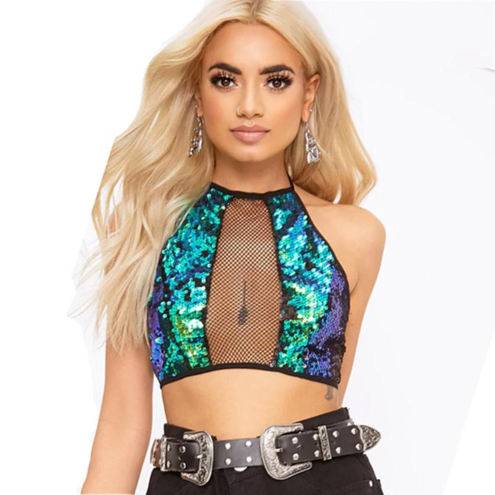 Woman with long wavy blonde hair modeling a vibrant iridescent sequin halter crop top featuring blue, green, and purple sequins with a sheer black fishnet mesh panel at the center. Styled with a wide black statement belt with large ornate silver buckles and matching dangling earrings.