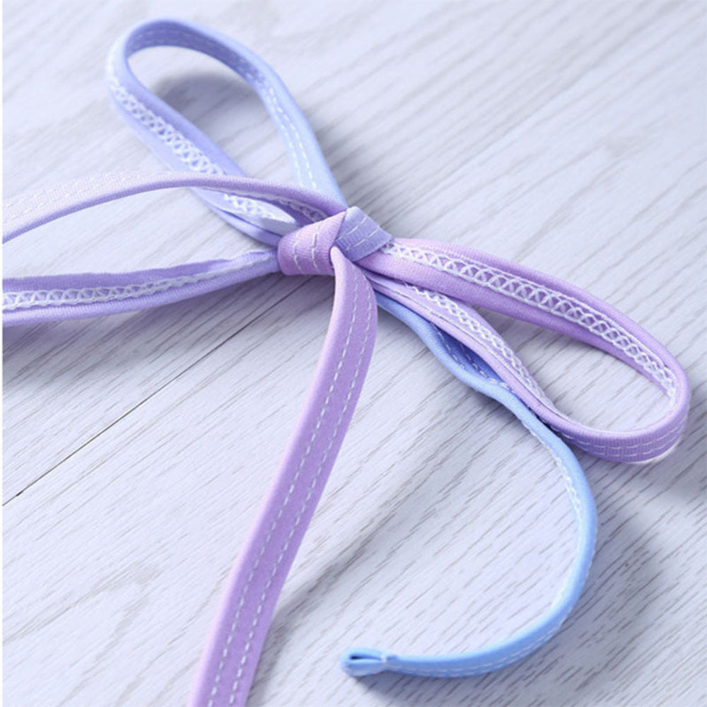 Purple shoelace with white stitching on a light wooden surface