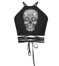 Black halter crop top with large white ornate sugar skull graphic print and multi-strap tie-back detail, shown flat lay on white background.