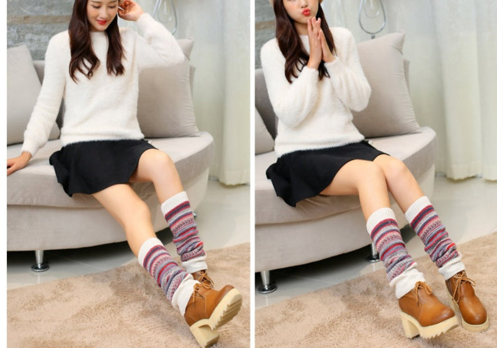 Woman wearing striped knit leg warmers over brown boots with a white sweater and black skirt.