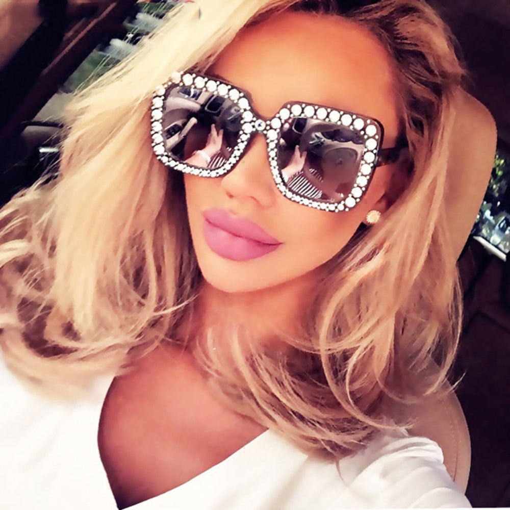 Women wearing black oversized square sunglasses with crystal-studded frames and dark lenses.