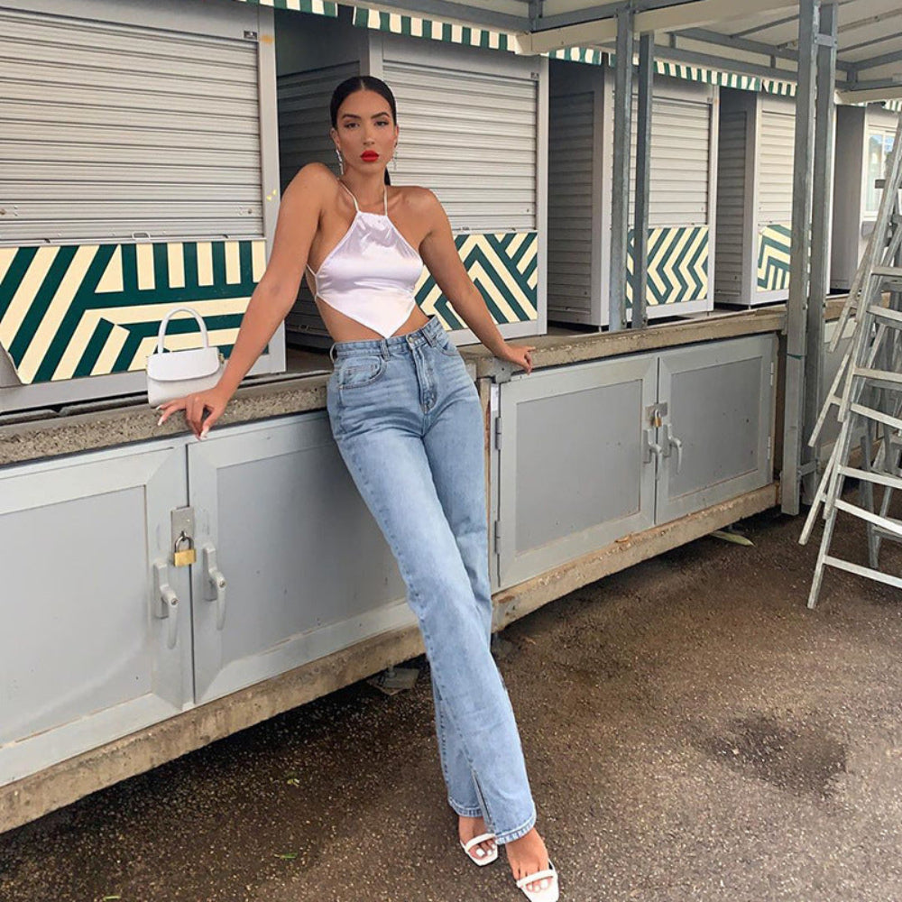 White halter cut-out crop top paired with light-wash straight-leg jeans, worn by a model posing at outdoor market stalls.