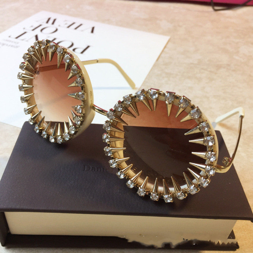 Cream round steampunk sunglasses with gold spikes, rhinestones, and brown gradient lenses, displayed on a brown box.