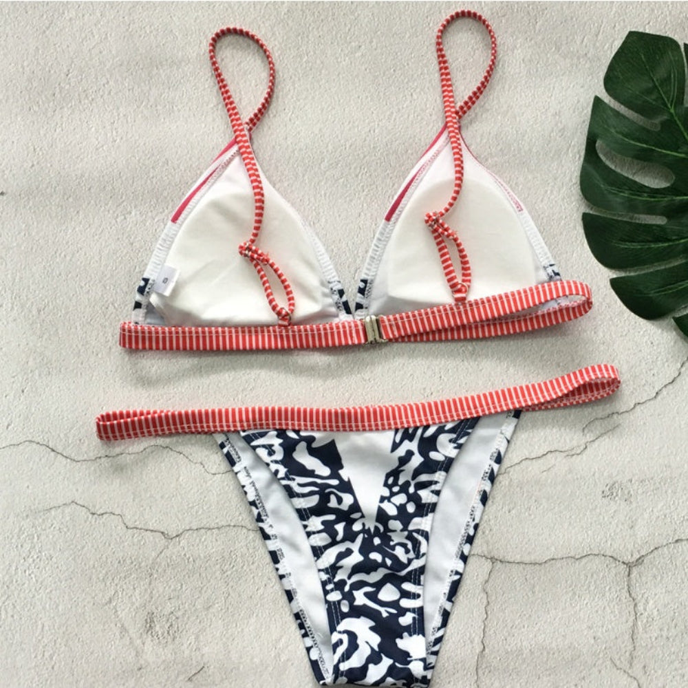 Bikini set with red and white striped straps on a textured surface.
