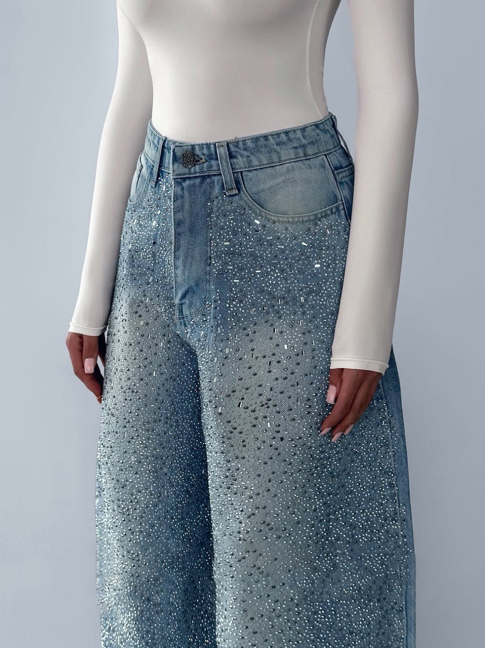 Light blue wide-leg jeans with heavy rhinestone embellishment on model.