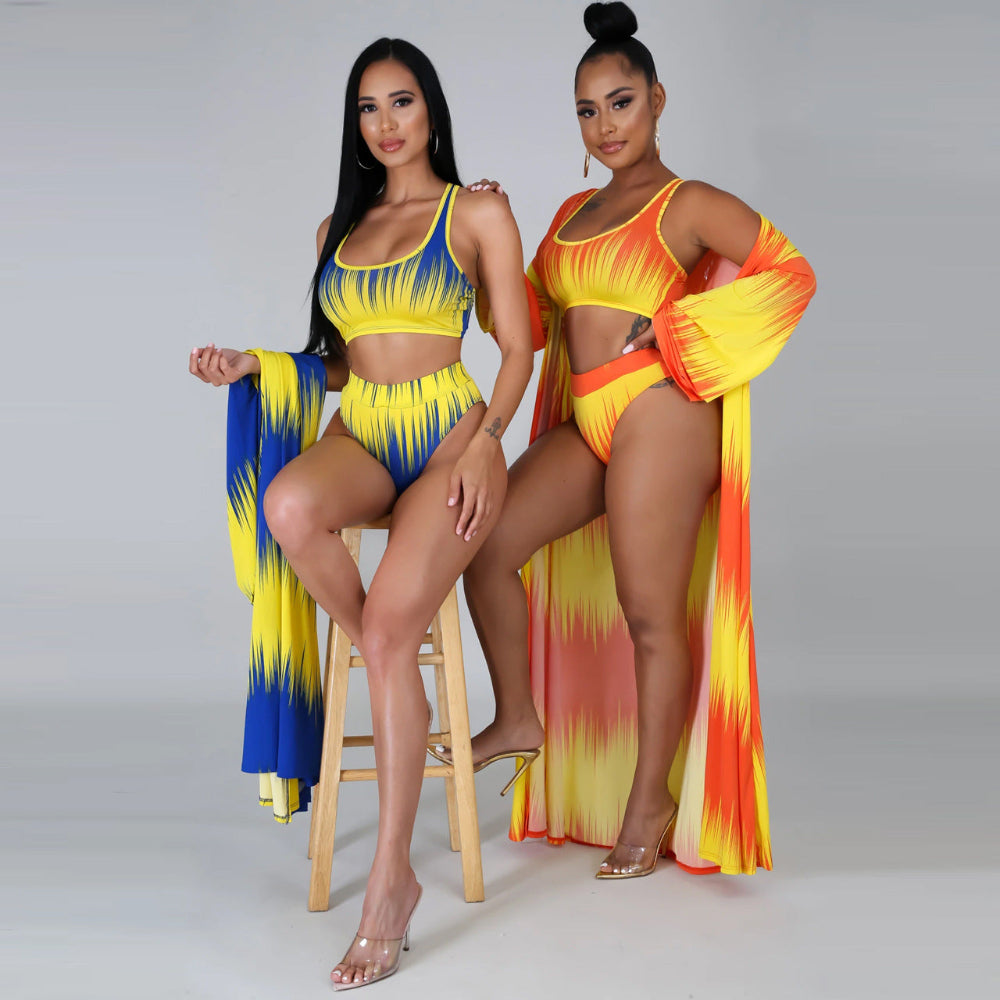 Two women in colorful swimsuits with matching cover-ups on a gray background