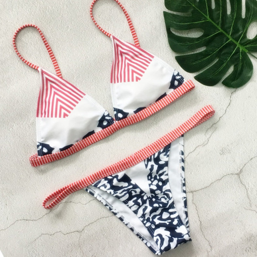 Bikini set with red and white striped and navy and white patterned design on a light stone surface.
