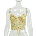 Yellow floral print ruched crop cami with thin adjustable spaghetti straps and tie-front hem, displayed on a clear mannequin.