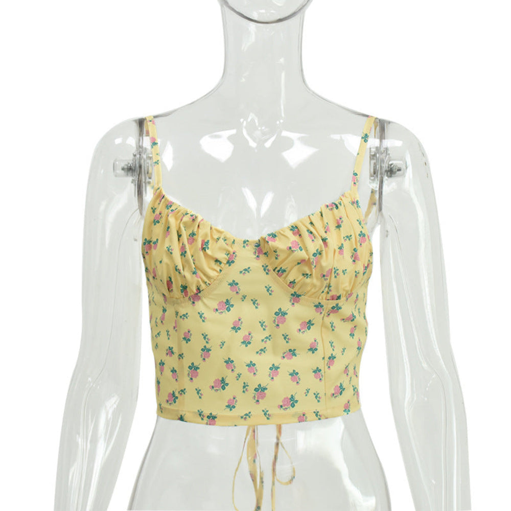 Yellow floral print ruched crop cami with thin adjustable spaghetti straps and tie-front hem, displayed on a clear mannequin.