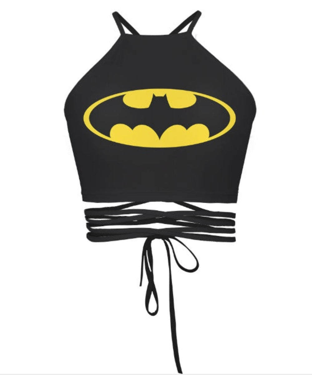 Black Batman halter crop top with yellow bat logo, multi-strap tie-back detail, shown flat lay on white background.