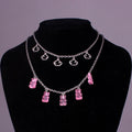 Multi-layered statement necklace set on a black display bust featuring a thick bright pink chain, delicate silver chains, a large pink star charm, translucent pink gummy bear pendants, and additional silver heart and clover charms. Bold and playful jewelry combination with silver lobster clasp.